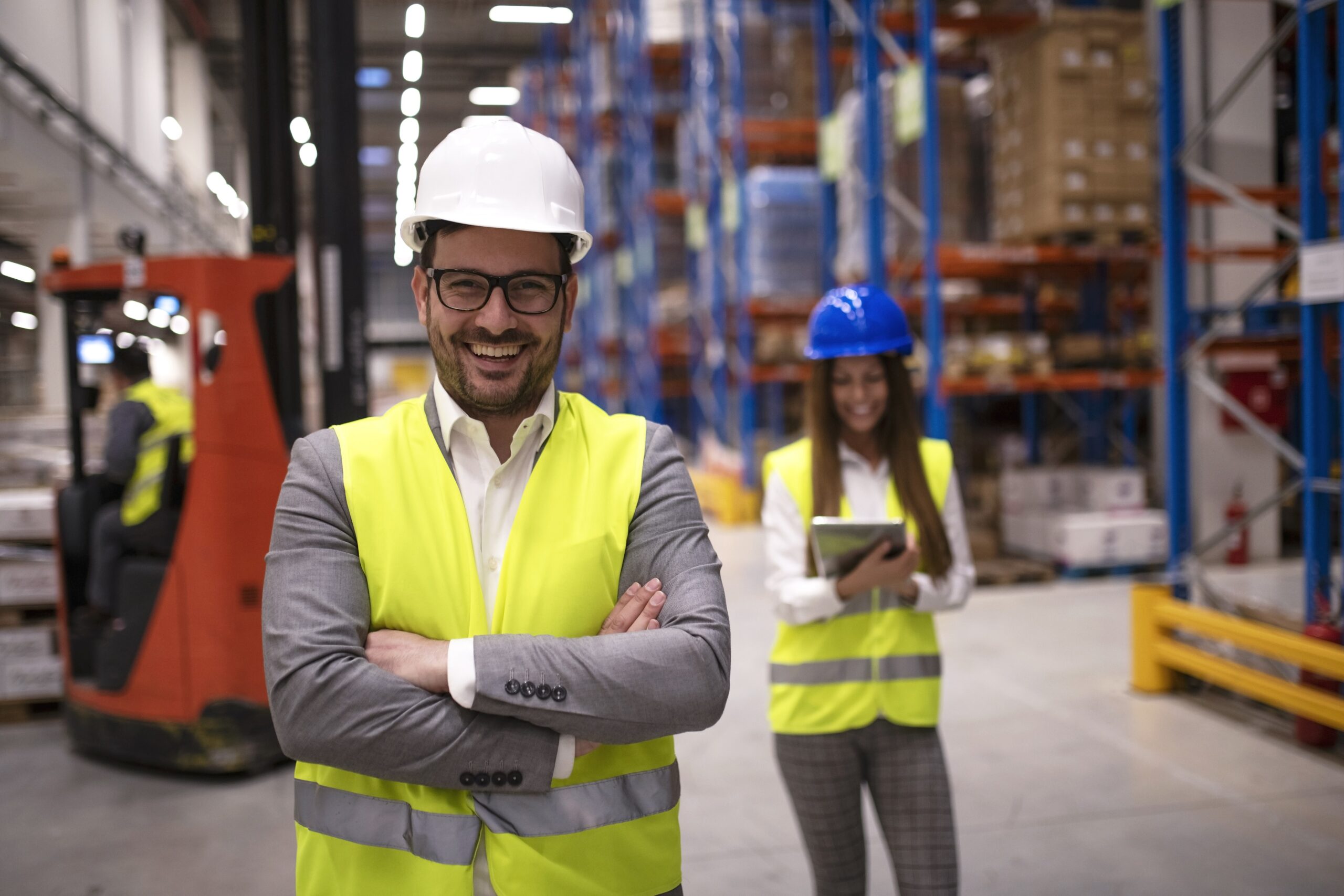 Portrait of successful warehouse worker or supervisor with crossed arms standing in large storage distribution area. Portrait of successful warehouse worker or supervisor with crossed arms standing in large storage distribution area.